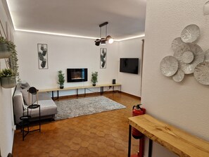 Bright and spacious living room with desk and work chair and flat screen TV.