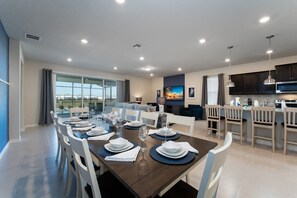 Experience open-concept living with a stylish dining area, modern kitchen, and cozy lounge opening to a scenic patio view.