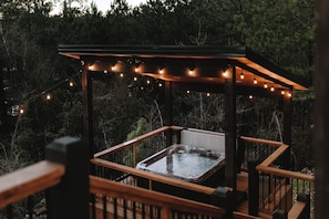 The hot tub sits on its own dedicated deck, surrounded by soft string lights, and amazing sunsets