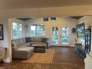 Living space with large sofa and smart TV overlooking the back yard