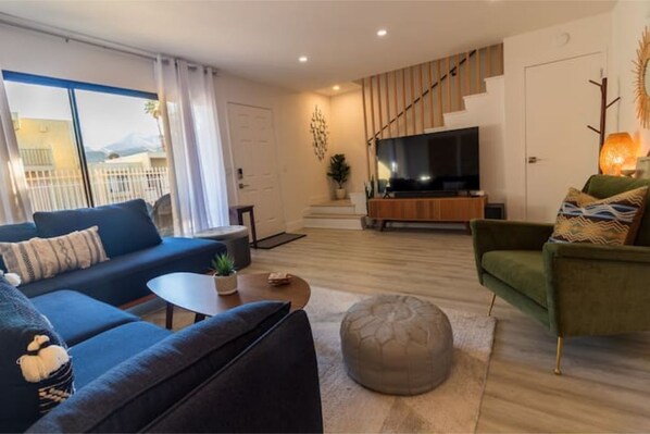Comfortable living room with mid-century meets boho desert design. 65" Smart TV.