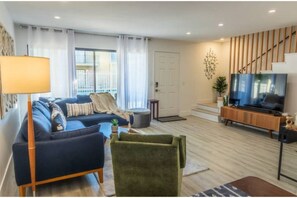 Comfortable living room with mid-century meets boho desert design. 65" Smart TV.