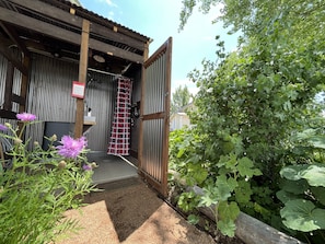 The outdoor shower has hot water, and is located behind the small blue cottage.