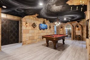 Wizard-themed game room with floating candles, spellbinding decor, and pool table.