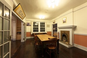 １F ダイニングルーム（夜）暖炉があるのもヴォーリズ建築の特徴の一つです。大きなダイニングテーブルでご夕食、ご朝食などをお持ち込み等いただいてお楽しみいただくこともできます。