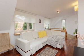 A spacious living room featuring a white sectional sofa, a coffee table, and bright natural light.
