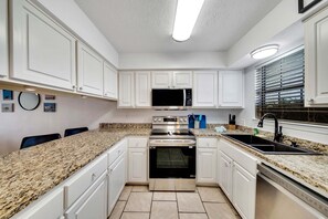 The fully equipped kitchen features granite countertops and BRAND NEW (2024) appliances and cookware.