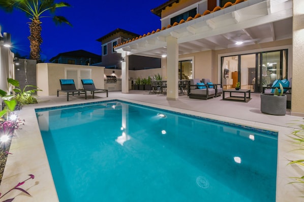 private backyard by night with pool, BBQ, and pagoda-covered dining and lounging