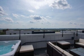 Large rooftop patio with hot tub and plenty of seating.