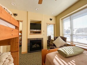 Experience the warmth and charm of this delightful bedroom, featuring a cozy fireplace and ample sunlight streaming through large windows. You will adore the perfect blend of comfort and scenic beauty, ensuring a restful stay.