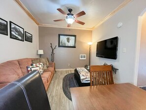 Enjoy a meal at the charming dining nook that offers a cozy space for intimate dinners. The combination of wood accents and modern amenities creates a welcoming environment for your culinary adventures. (Large main living area with pull-out sofa, dining area, and flatscreen TV)