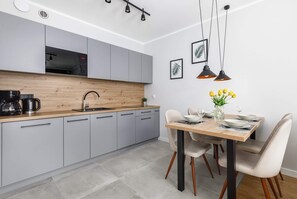 A small kitchenette with gray cabinets and wooden countertops. A dining table with chairs is adjacent, completing the compact layout.