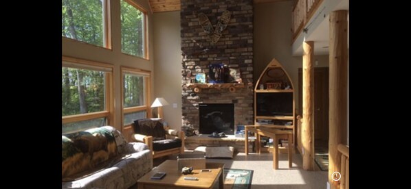 Living room with gas fireplace and a wall of windows to view lake