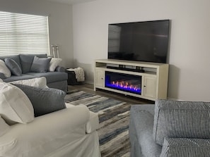 Living room features 75" smart TV and fireplace.