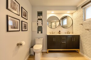 Modern bathroom with double sinks, round mirrors, and stylish decor.