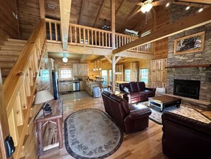 This is the view as you walk in the front door of the cabin. You will see a large open area with a view of the kitchen, the dining area, the living room, and the fireplace. 