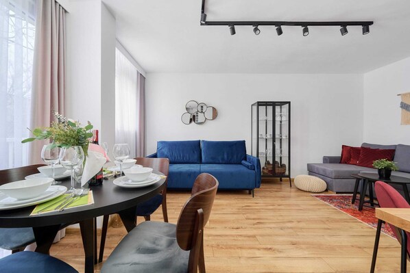 A stylish living room with a blue sofa, wooden furniture, and a cozy dining area, creating a warm atmosphere.
