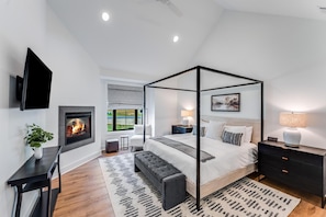 Main level bedroom with fireplace and king bed and vaulted ceiling.