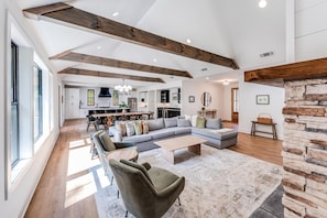 Spacious light-filled main level great room with fireplace and large windows.