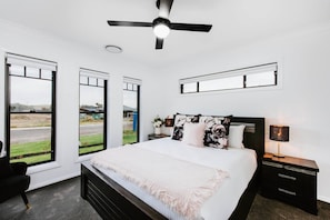  The primary bedroom features a king-size bed with side tables and reading lamps, as well as a ceiling fan and modern ensuite. 
