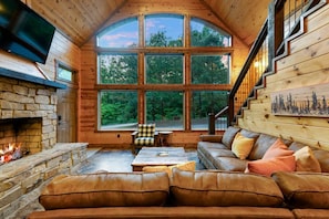 Immerse yourself in the tranquility of this cabin, featuring tall windows that seamlessly integrate the interior with its natural surroundings.