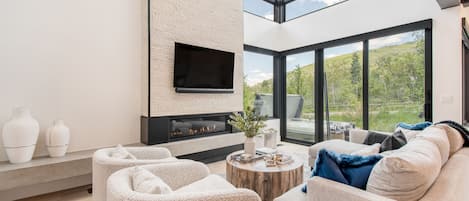 Modern living room with tall ceilings, large windows, and an electric firepit.