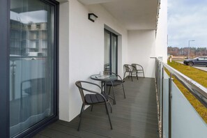 A balcony area with a small table and chairs, ideal for enjoying outdoor relaxation. The view overlooks the apartment complex and its surroundings.