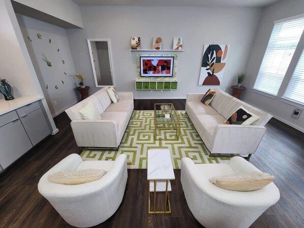 Intimate living area with two sleeper sofas and boucle comfy chairs. Onlooking 55 inch smart TV