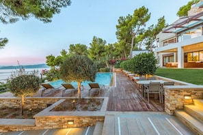 Villa Corinthia's Panorama: Poolside Splendor with Saronic Gulf Views. Here, you can enjoy the expansive poolside areas where you and your children can play or simply relax on the sunbeds, basking in the gentle caress of the sun's rays.