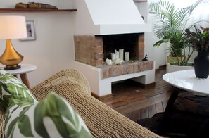 Bright living room with design pieces, art, antique floors & romantic fireplace