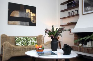 Sunny living room featuring stylish decor, artwork, vintage floors and fireplace