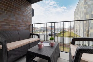 A cozy balcony with a black wicker table and chairs, overlooking a modern residential area. Perfect for enjoying coffee or relaxing outdoors.