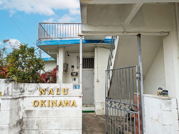 ・[Exterior] The yellow sign of nalu.okinawa and the Shisa on both sides are landmarks.