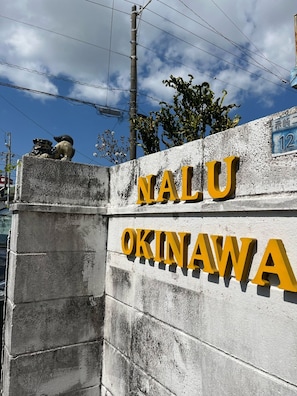 A yellow signboard and Shisa are landmarks