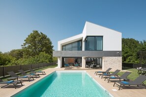 Heated pool on the terrace in the private yard of the family villa for rent Aria and an outdoor table with chairs in front of the entrance to the ground floor of the villa