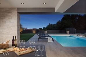 Blick auf den privaten Garten und Pool vom Esstisch im überdachten Teil der Terrasse der Villa Aria Liznjan