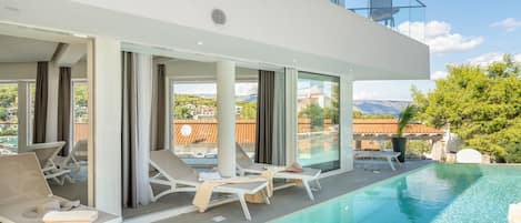 View of the outdoor terrace with deckchairs by the pool in Croatia luxury villa Ideali in Vrboska