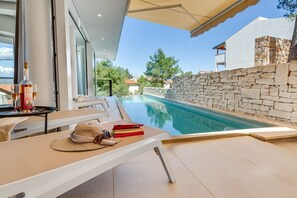 View of the infinity heated pool from the outdoor terrace of Croatia luxury villa Ideali with a view of the sea in Vrboska