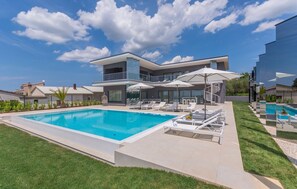 The courtyard of the luxury villa Nimai Luce with a landscaped lawn and an outdoor pool in Istria