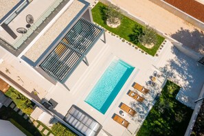 Upper perspective on the Luxury Villa Idria Sea and View with private heated pool, patio with loungers, olive trees, balcony with outdoor furniture, mobile grill and roofed terrace 