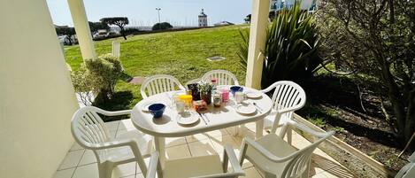 Terrasse donnant sur espace vert vue port de plaisance et restaurants.