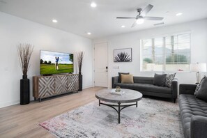 A living room setup with a sectional fee with a large flat-screen TV.