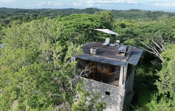 Aerial shot of the tower with the ocean in the background, main house on left