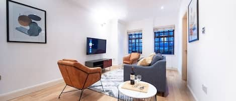 Relax in this chic living room with modern-minimal decor, a comfortable sofa and armchairs, and a flat-screen TV for streaming Netflix & Disney+. The trendy ambience makes it great for hosting friends or enjoying a quiet night.