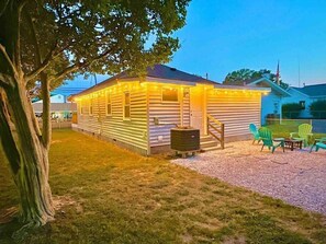 Backyard side view at night with decorative lights & mature trees