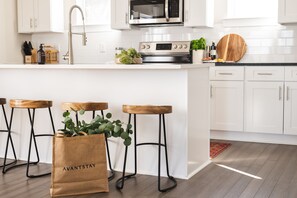 Kitchen features modern appliances and an island with a breakfast bar.