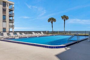 Oceanfront pool with lounge chairs and views of the waves beyond.