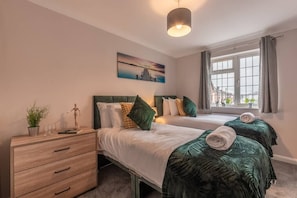 Twin bedroom with chest of drawers and bedside table. 