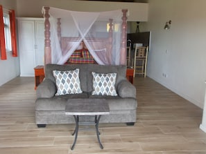 4-poster bed with canopy mosquito nets and sofa with view of natural habitat.