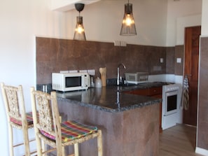 Kitchenette with granite top & volcanic stone wall tiles doubles as dining table